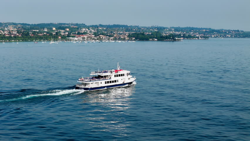 Passenger ferry mid-lake on Lake Garda en route to the next stop, aerial Public transport operation on a fixed timetable