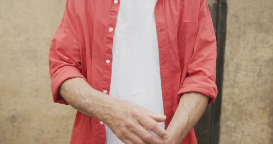 Man rolling up red shirt sleeves and initiating zoomout for fashion ad with blue dotted overlay. Casualstyle, confident, streetwear, urban, lifestyle, modern, architecture