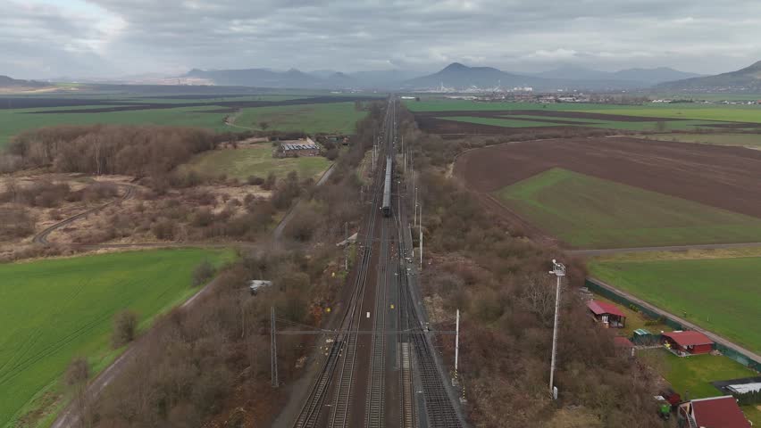 Aerial drone view of railway stretching into distance with mountains on horizon, symbolizing journey, transport, freedom, and scenic landscape.
