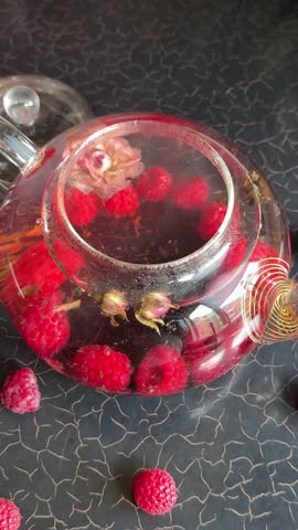 raspberries, rose petals, berries Process brewing tea, ceremony, Cup of freshly brewed fruit herbal. poured from the kettle into a cup with tea leaves. tea with raspberries and blueberries, lemon mint