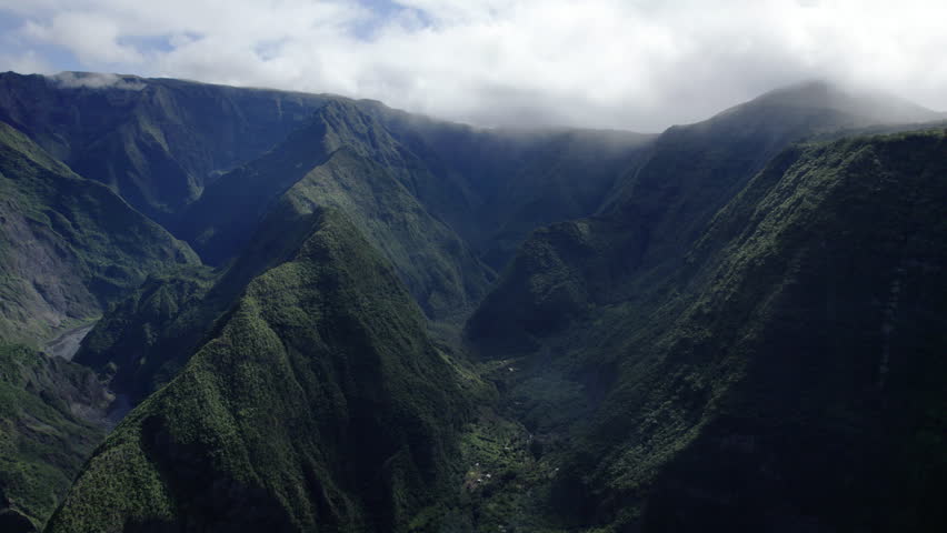 Vertiginous aerial view from Bois Court viewpoint showing Grand Bassin, rolling hills, and vast verdant landscapes of Reunion Island. Expansive tropical scenery.