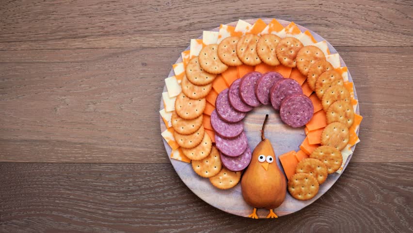 Thanksgiving turkey theme cheese board. Stop motion placement, Top down view on a wood background.