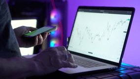 Close up of smartphone in hand and laptop screen with financial chart glowing in modern workspace. Represents digital finance, investment, technology and multitasking. - Powered by Shutterstock - Get 15% off with code: PIKWIZARD15