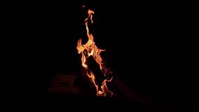 Isolated fire burns in deep night, orange tongues curl around stacked logs as smoke drifts and embers glow. Minimal background and high contrast emphasize heat, flicker, and a moody atmosphere. - Powered by Shutterstock - Get 15% off with code: PIKWIZARD15