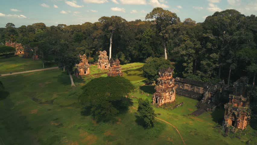 Cinematic aerial drone shot over Suor Proat temple towers near Angkor Thom, Cambodia. Ancient Khmer architecture surrounded by jungle forest, perfect for cultural heritage, tourism, and promo use.