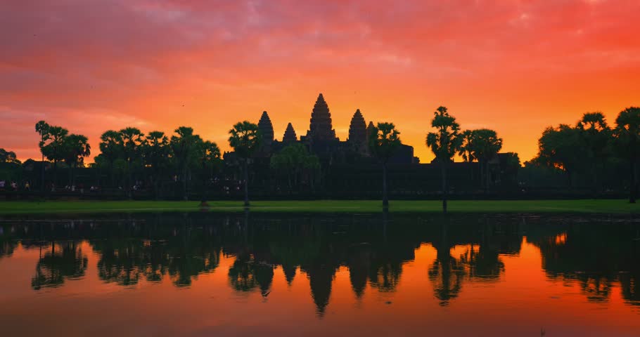 Accelerated time lapse footage of tourists visiting Angkor Wat in Cambodia as the sun rises with colorful skies. A cinematic UNESCO heritage landmark scene perfect for travel, culture and promo