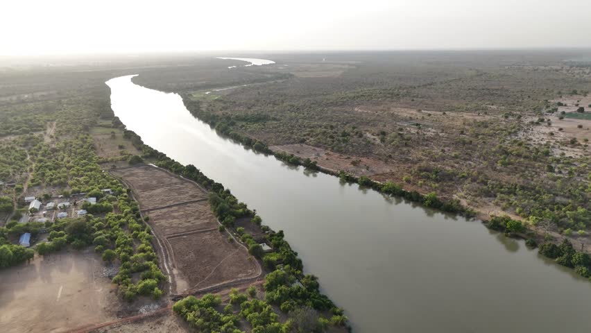 Wide drone shot of the Gambia River flowing through rural landscapes at dusk