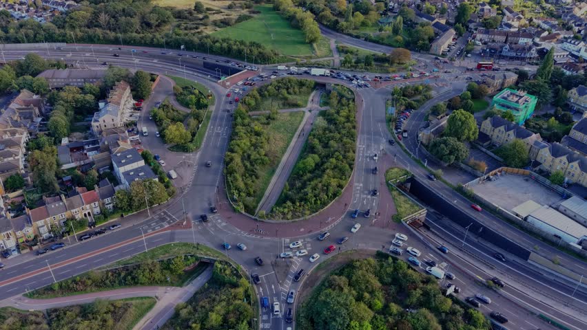 Aerial hyperlapse of the Green Man Roundabout, Leytonstone, London. Drone orbits, creating a clockwise rotating effect as long afternoon shadows, passing clouds, and sunlight play across the scene.