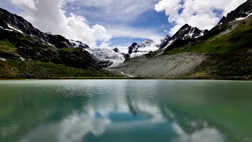 Clouds reflect in the lake at the foot of snowcapped mountains