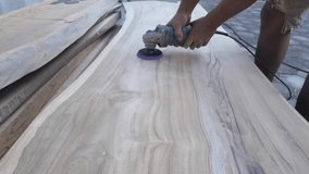 Close-up video of a carpenter sanding a large wooden slab with an electric grinder. Detailed footage of woodworking craftsmanship, smoothing the wood surface, carpentry process.  - Powered by Shutterstock - Get 15% off with code: PIKWIZARD15