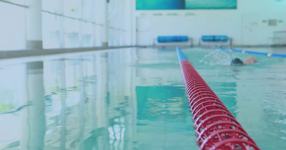 Fitness swimmer breaking water at lane end grasping red rope catching breath revealing next swimmer. Athlete, sportive, aquatic, training, wellness, minimalist, energizing