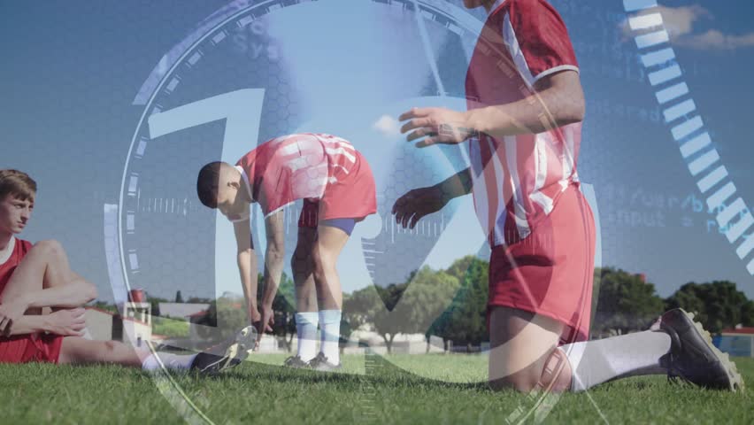 Transparent HUD rotating starting countdown while players stretching hamstrings in soccer training. Athletes, fitness, technology, sportswear, outdoor, teamwork, stamina