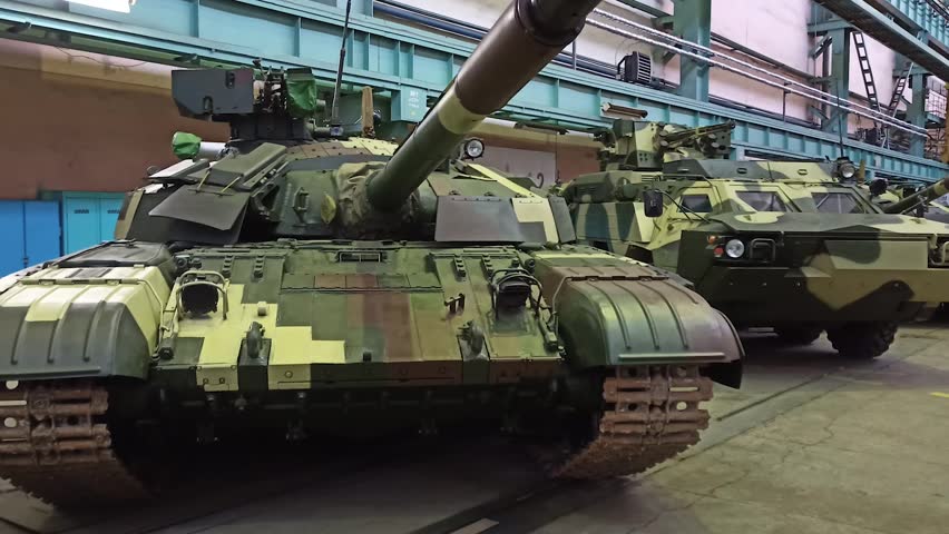 Several tanks stand in the hangar of a military plant. Production and maintenance of heavy armored vehicles. Military industry.