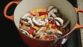 Colorful Sliced Peppers and Mushrooms Simmering in an Orange Enamel Dutch Oven - Powered by Shutterstock - Get 15% off with code: PIKWIZARD15