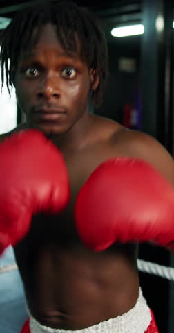 Black man, face or punching with boxer in arena for self defense, tournament or spar match in gym. Portrait, male person or fighter with boxing gloves in POV for fighting challenge in knockout ring