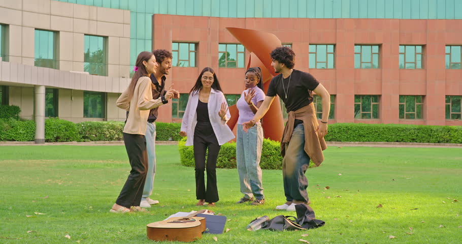 Indian young adult gen z man woman group team do funny dance together have fun joy outdoor campus place. Happy smiling teen age girl boy spend break time enjoy new day in fresh air outside garden park