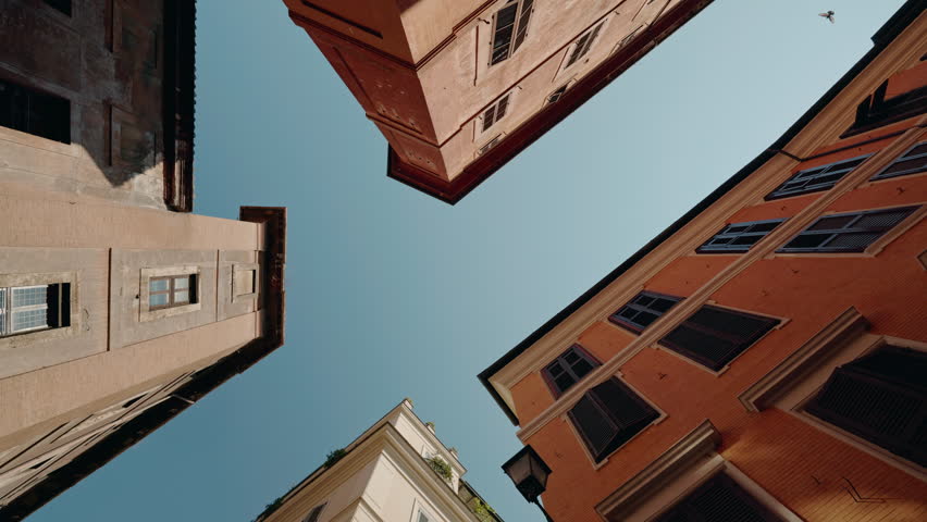 Rotating view from below between four colorful Roman buildings with open shutters. High quality 4k footage