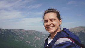 A cheerful young woman takes a selfie against the backdrop of mountains during her trip - Powered by Shutterstock - Get 15% off with code: PIKWIZARD15