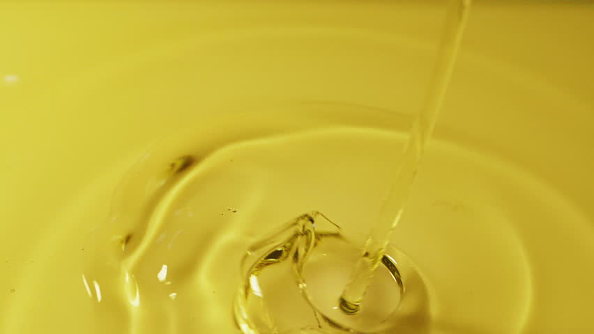 Slow motion shot of palm oil drops floating in water on white background.
