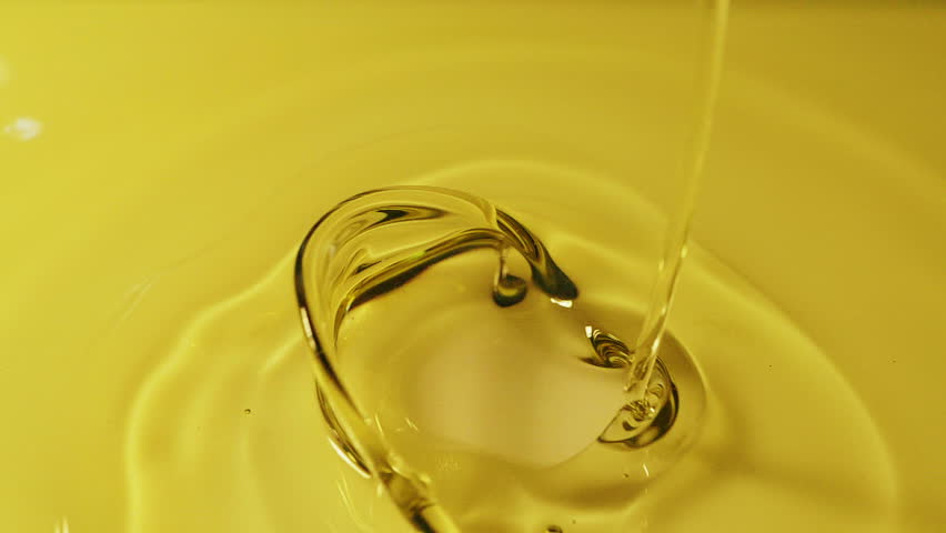 Slow motion shot of palm oil drops floating in water on white background.
