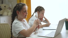 Girl studying online at home with laptop and notebook while sibling writes at desk and girl holds score paddle smiling during study and learning session with tutor supporting education child focus - Powered by Shutterstock - Get 15% off with code: PIKWIZARD15