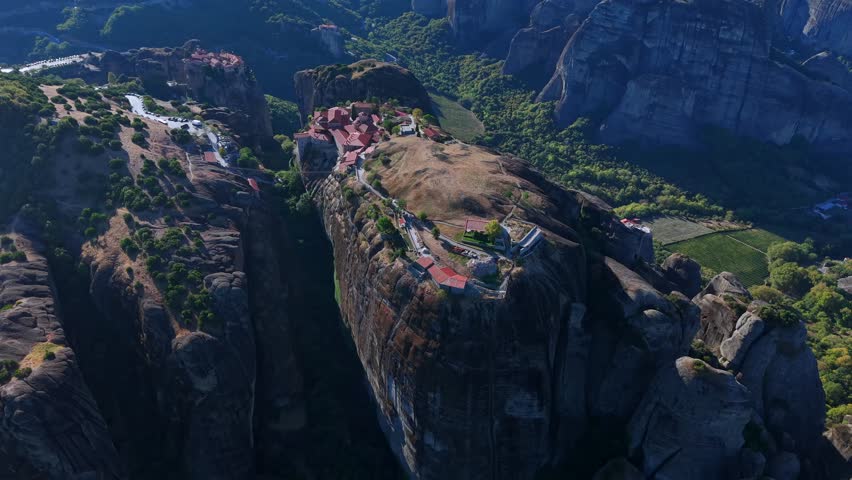 Aerial View of the Great Meteoron Monastery atop Towering Rock in Meteora and town houses of Kalambaka, Greece
