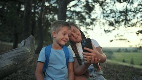 Tablet lights face of girl and boy in forest. Children focus on screen, children smile. Sibling takes selfie, sibling bonds. Forest holds still. Selfie shows moment. Girl clicks, tablet stays bright. - Powered by Shutterstock - Get 15% off with code: PIKWIZARD15