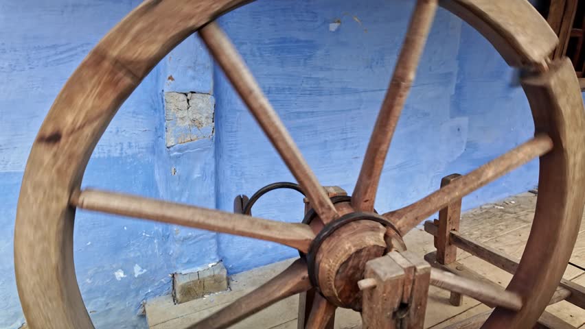 Old broken traditional wooden craft spinning wheel rocks to and fro