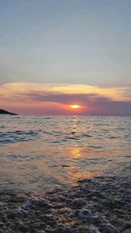 sunset. A fisherman in the distance is fishing on a boat. beautiful sandy beach, waves crashing on the shore.