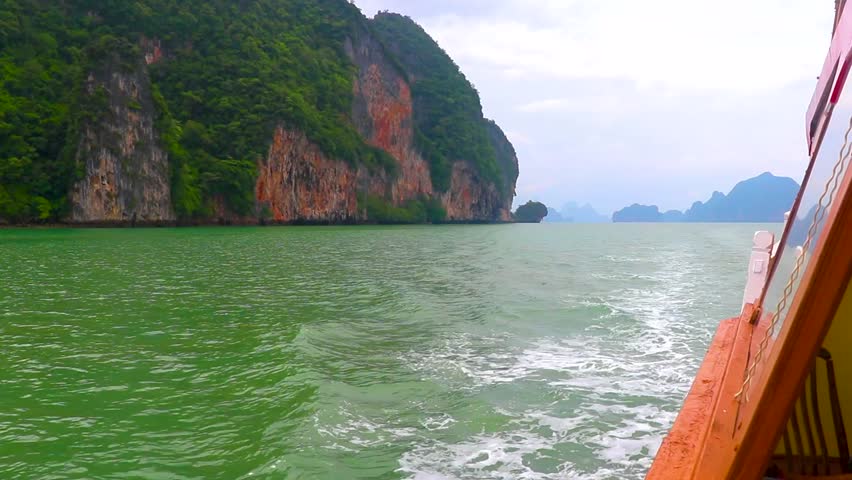 Tourist ship boat at the limestone rocks hills mountains panorama seascape and turquoise green water with blue cloudy sky in Krasom Amphoe Takua Thung Phang Nga Thailand in Southeast Asia.