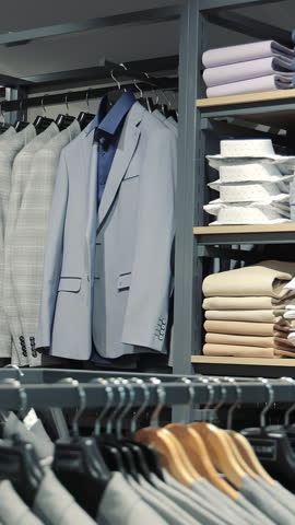 Display of formal shirts and suits in a retail clothing store. A neatly organized retail display of formal shirts and suits, showcasing a variety of folded dress shirts in different colors and
