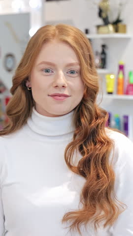 Smiling woman with curly red hair in beauty salon.