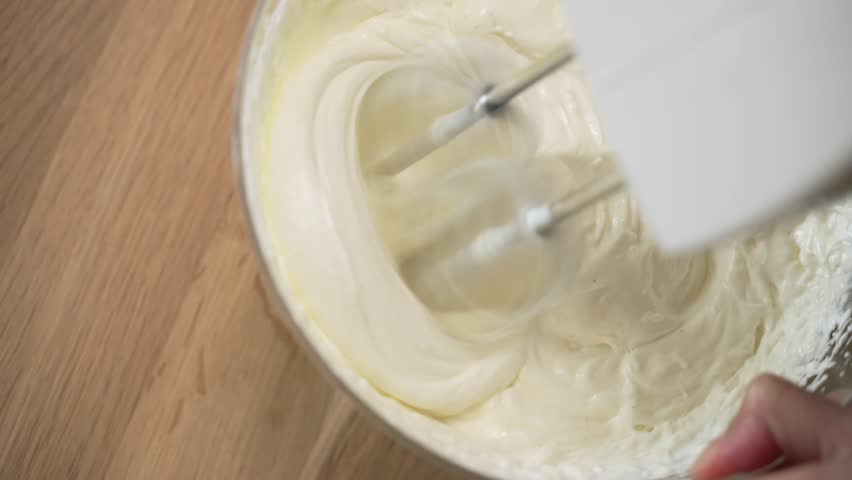 Whipping a Cream and the ingredients for baking with a mixer. Whipped cream, whisk for whipping. Cooking dessert, cake.