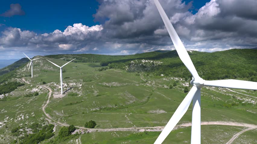 Wind power generation in natural mountain environment: Scenic mountain valley with modern wind turbines producing sustainable electricity.