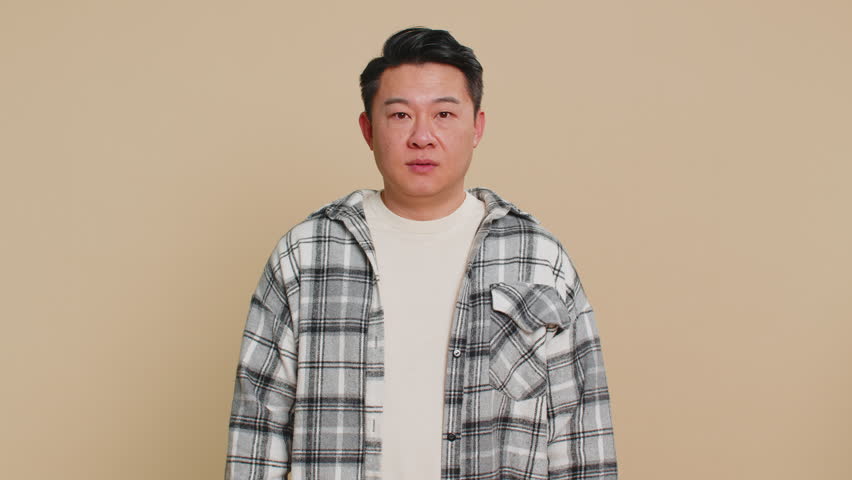 You are crazy, out of mind. Confused Asian middle-aged man pointing at camera and showing stupid gesture, blaming asking some idiot for insane plan, bullying. Mature Chinese guy on beige background