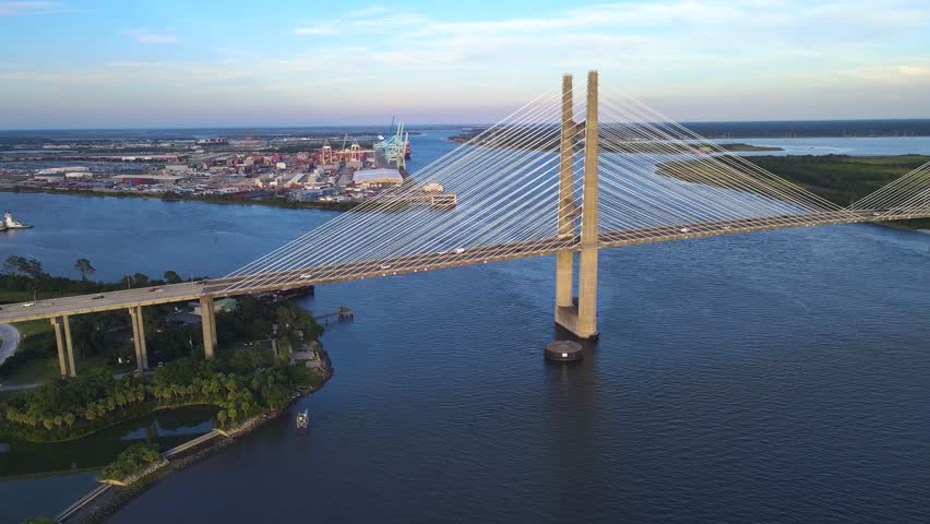 Golden light illuminates the Dames Point Bridge. Sunset reflections enhance the Florida skyline.
