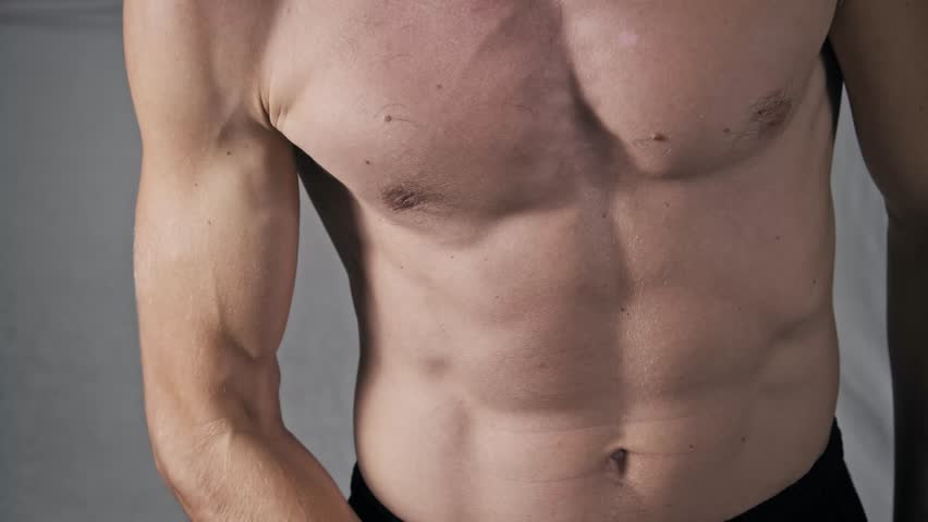 Macro view of a fit man's arm as he performs a bicep curl with a black elastic band. The focus is on the muscle definition and veins during an intense home gym workout session.