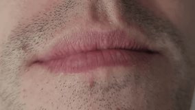 Macro shot of an unshaven man's lower face. He gives a slight, subtle smile or smirk, showing his upper teeth and the texture of his lips and stubble against a plain gray studio background. - Powered by Shutterstock - Get 15% off with code: PIKWIZARD15