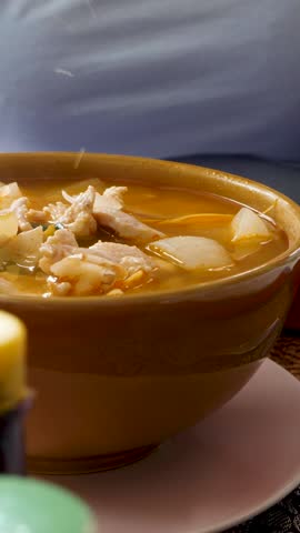 Traditional Thai Tom Yum soup with shrimp served in brown bowl with spoon. Hot and sour broth rich with herbs and spices. Fresh vegetables and seafood ingredients for homemade cuisine 