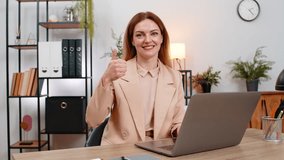 Middle-aged businesswoman at home office checks results on laptop smiles shows thumbs up gesture approves work. Freelancer girl at table confirms success sends file writes note celebrate progress - Powered by Shutterstock - Get 15% off with code: PIKWIZARD15