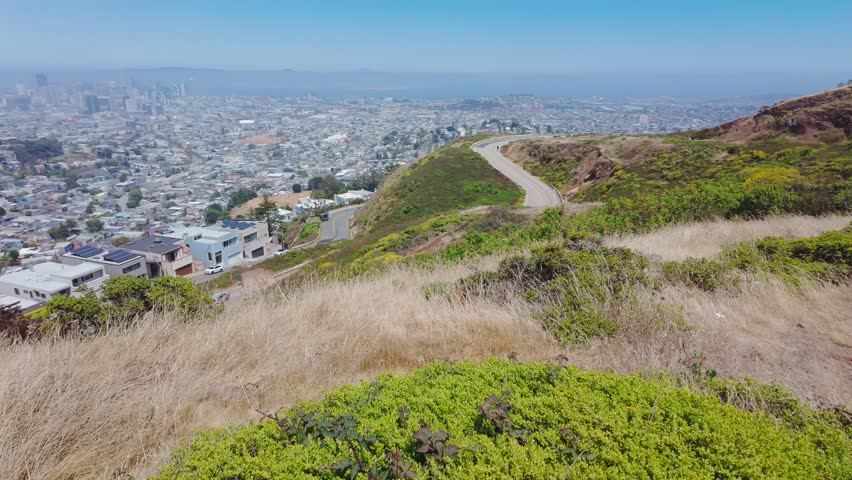 Panoramic view of San Francisco skyline from Twin Peaks, California, USA. Winding road, residential houses and downtown skyscrapers visible on a clear summer day