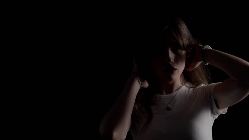 Studio portrait of a young woman turning her head and looking over shoulder against a black background