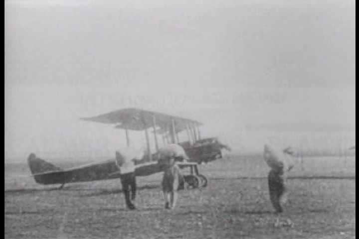 1910s - Early aviators walk on the wings of a biplane to dump grain over fields below.