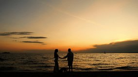 Silhouette couple walks hand in hand along the beach at sunset, creating a peaceful romantic moment against the calm sea and warm sky. - Powered by Shutterstock - Get 15% off with code: PIKWIZARD15