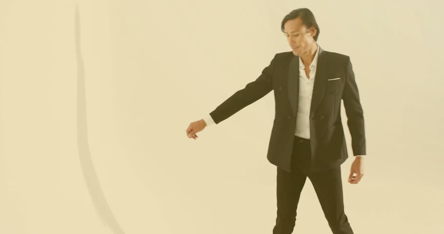 Model reacting to drifting light orbs lifting arm guiding them near beige backdrop for fashion ad. Abstract, elegance, sophistication, illumination, cinematic, minimalism, professionalism