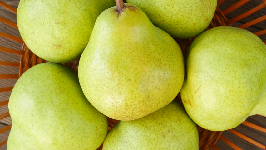 Ripe organic pears spinning in a basket, showcasing their natural texture and color.