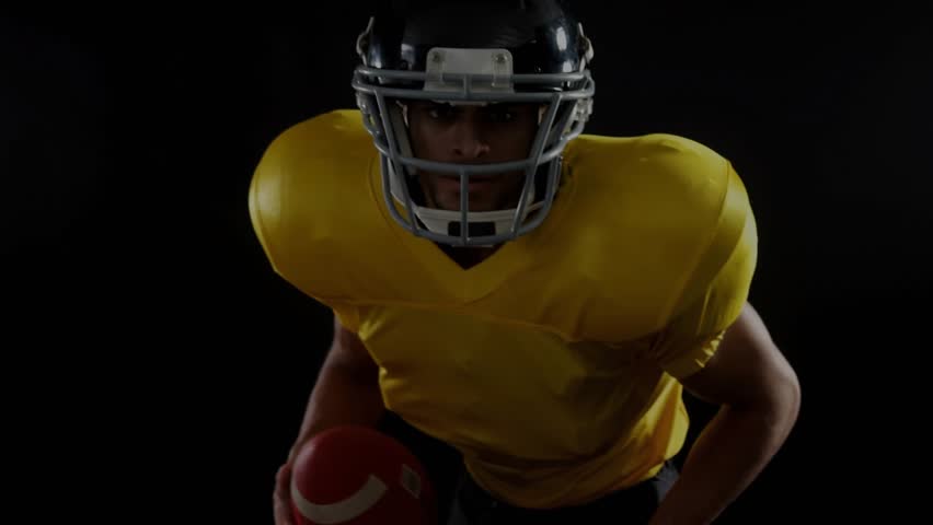 Football player holding ball in dark set initiating emerging data overlays for performance analysis. Athlete, sports, technology, digital, analytics, performance, innovation - Powered by Shutterstock - Get 15% off with code: PIKWIZARD15