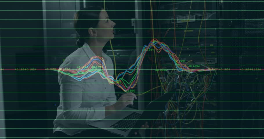 Technician observing pulsing charts on laptop, tracing rack cables and monitoring network metrics. Technology, data center, cybersecurity, connectivity, diagnostics, infrastructure, engineering