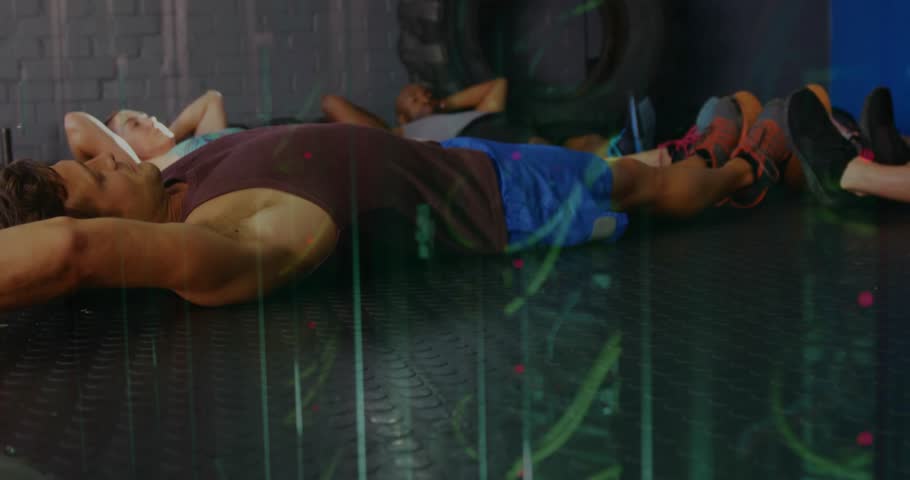 Leader in purple tank initiating V-sit core exercise on gym mats while group following for fitness. Fitness, groupwork, strength, conditioning, training, athletic, workout