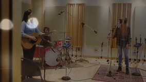 Female guitarist, drummer and vocalist putting on headphones, checking mix and recording tight take. Studio, music, performance, recording, acoustic, live, collaborative - Powered by Shutterstock - Get 15% off with code: PIKWIZARD15